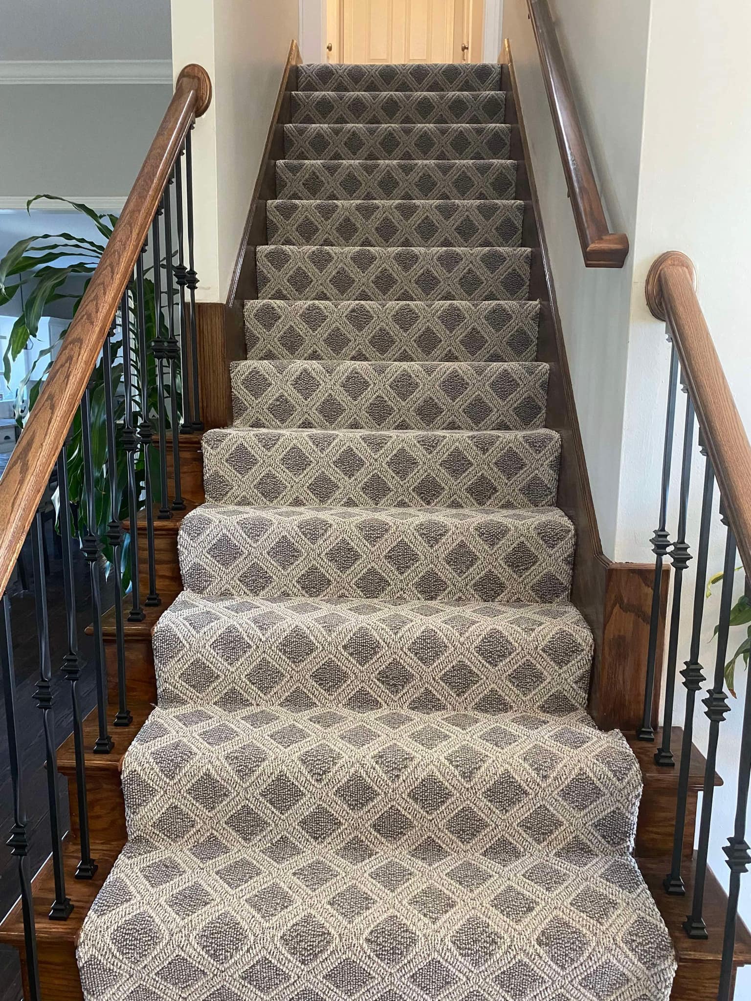 Staircase carpet runner with diamond pattern on hardwood stairs
