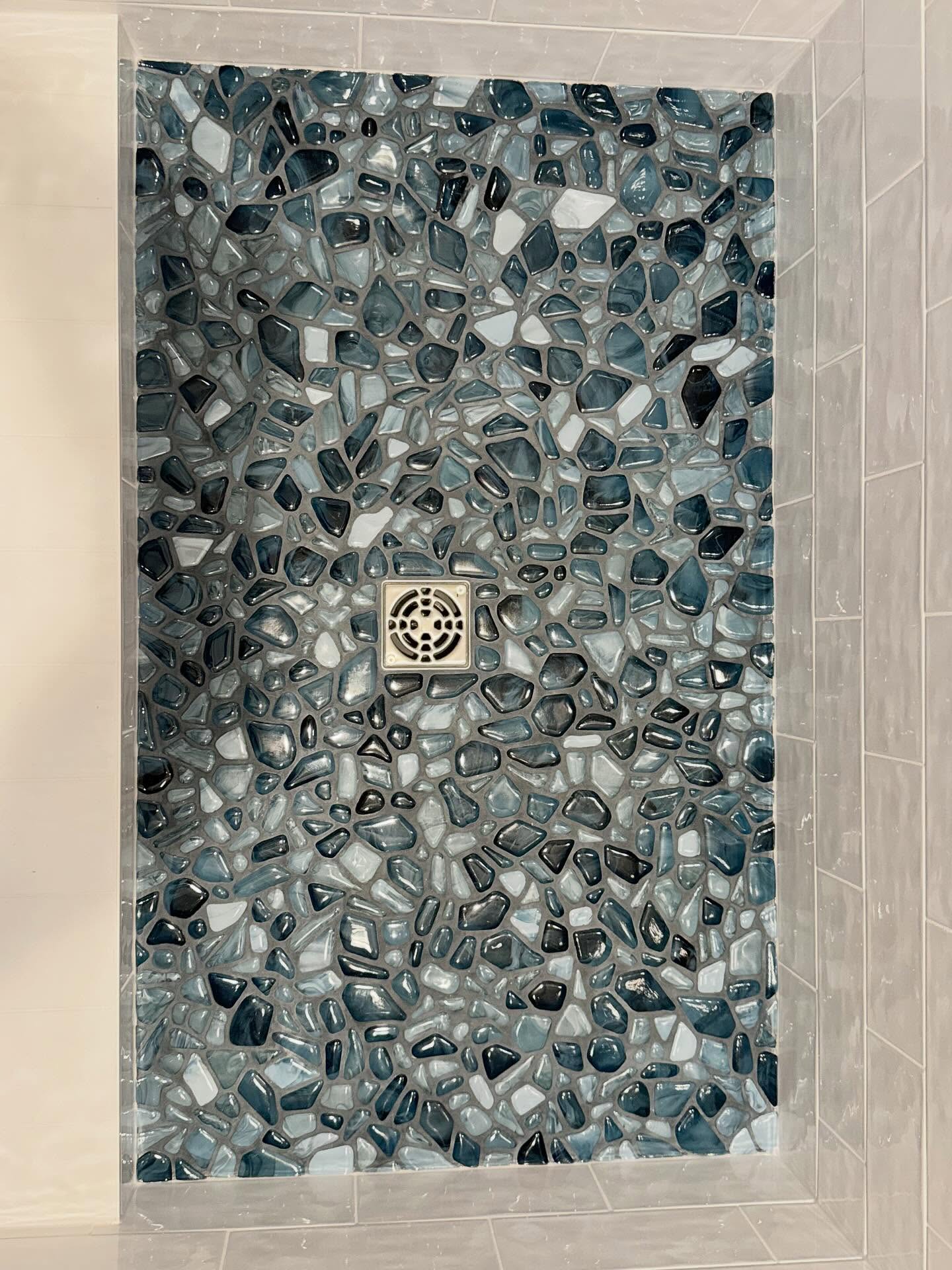 Custom pebble stone shower floor with blue and gray mosaic tile