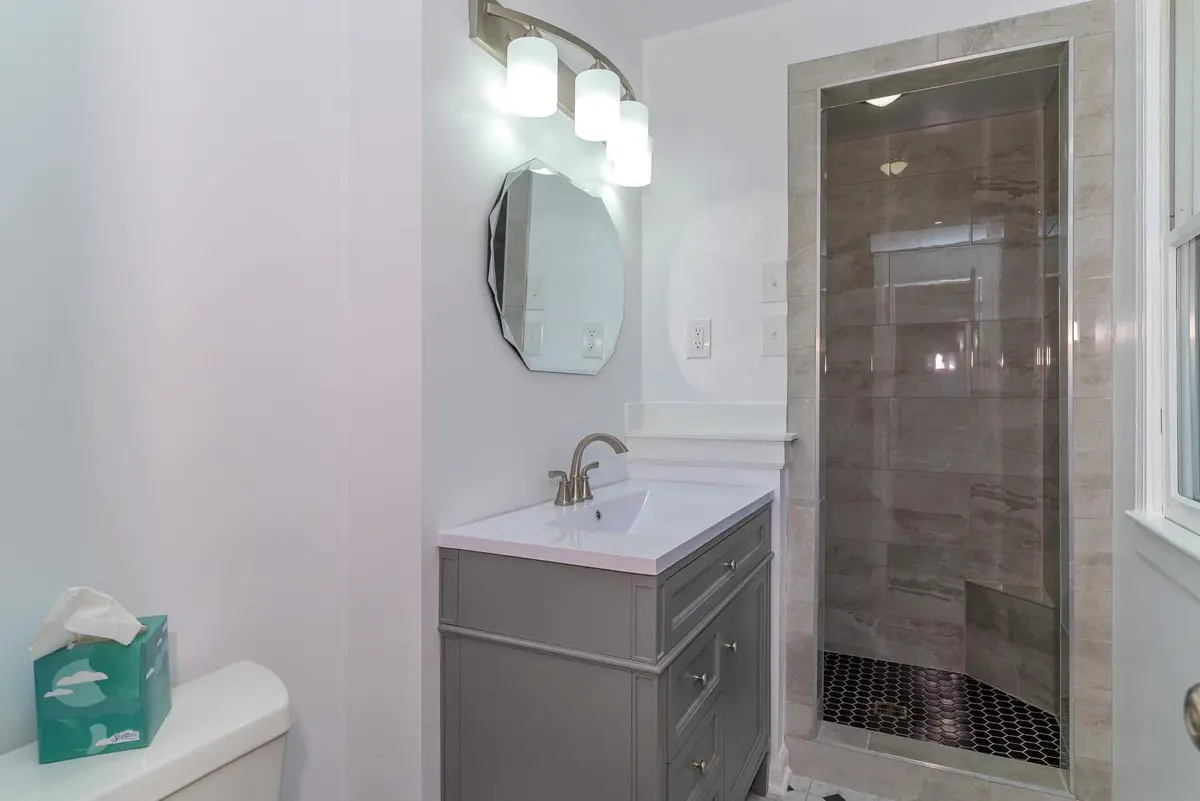 Bathroom remodel with a gray vanity and a walk-in tile shower