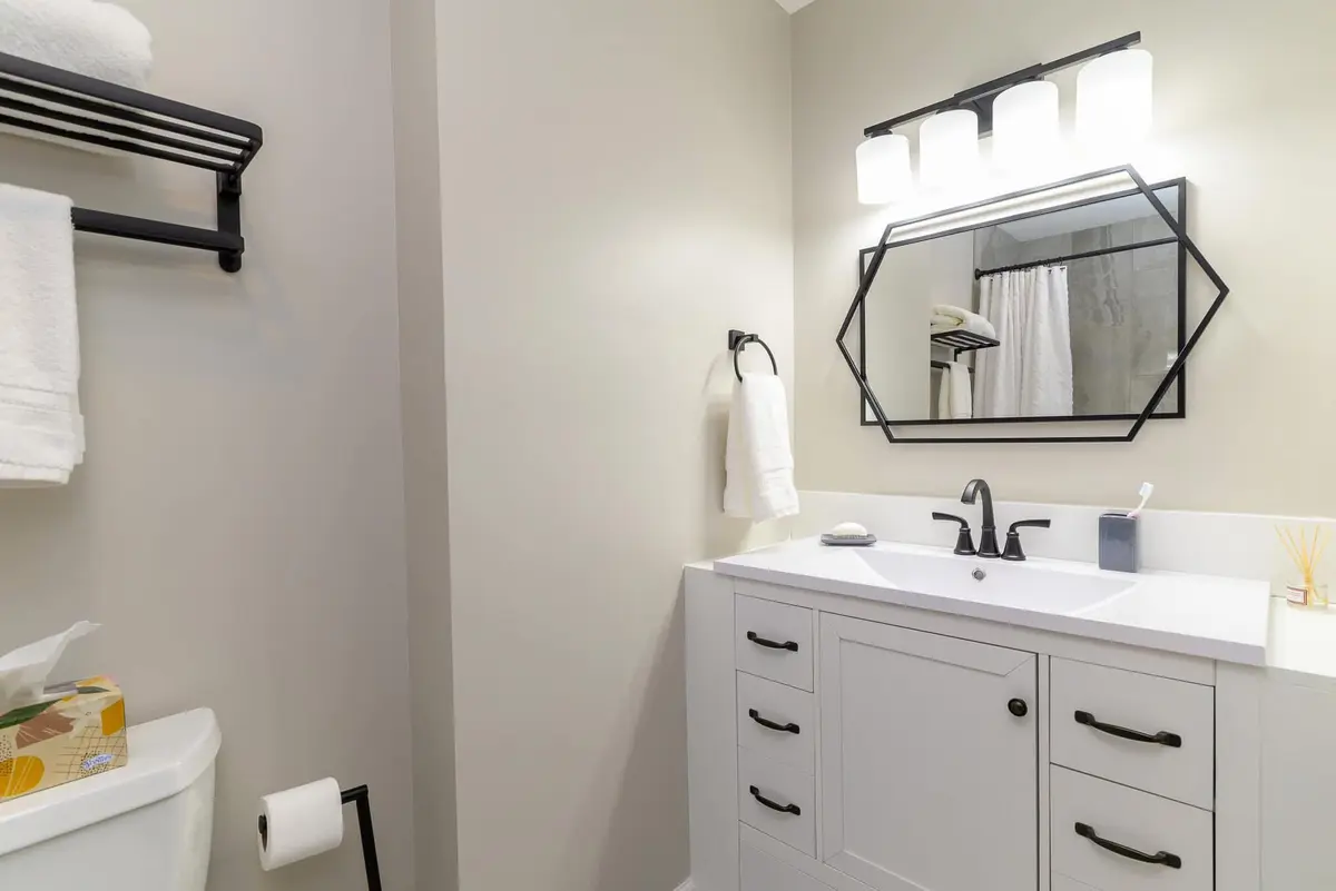 Elegant bathroom with white vanity and geometric black-framed mirror