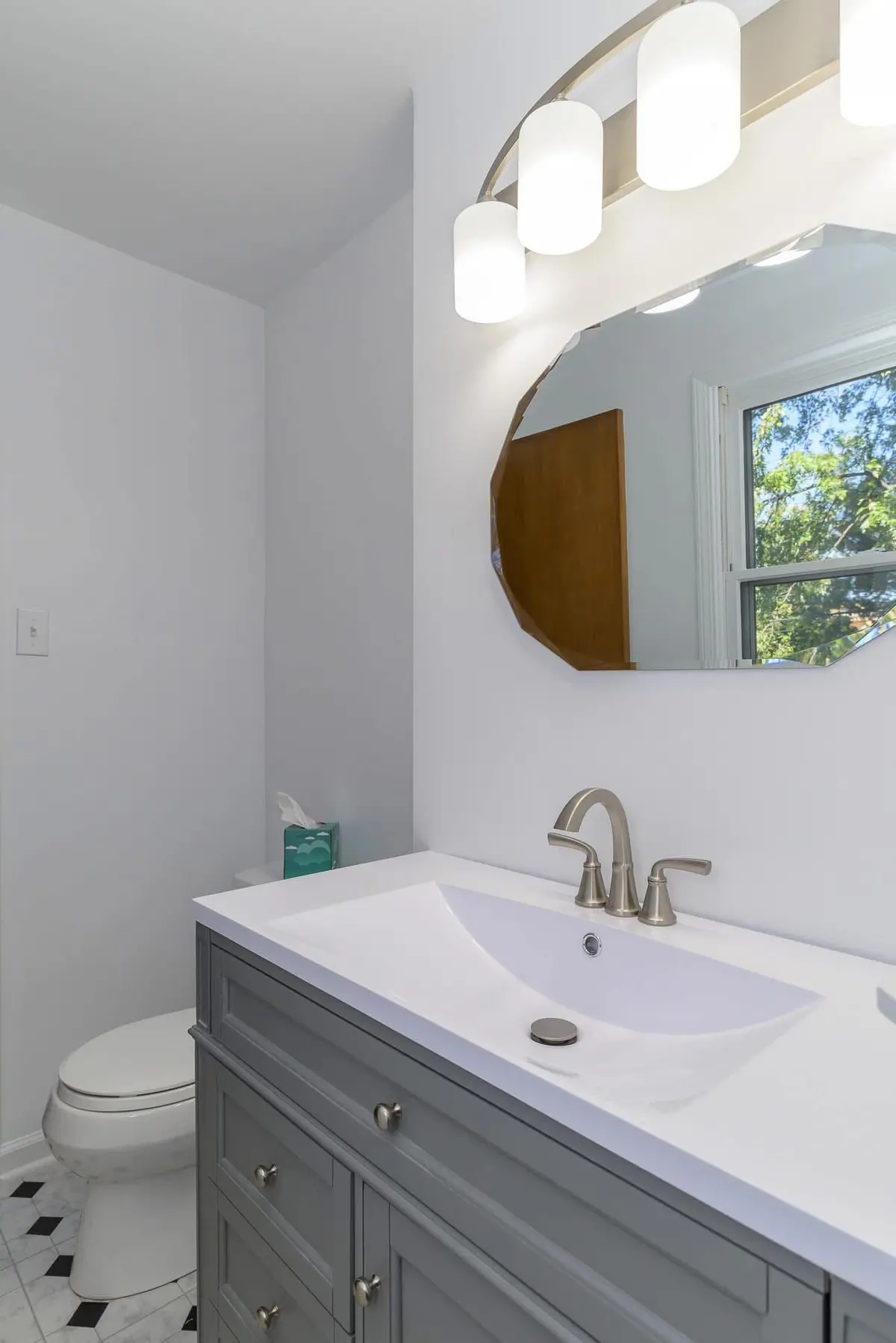 Updated bathroom vanity with gray cabinet and oval mirror