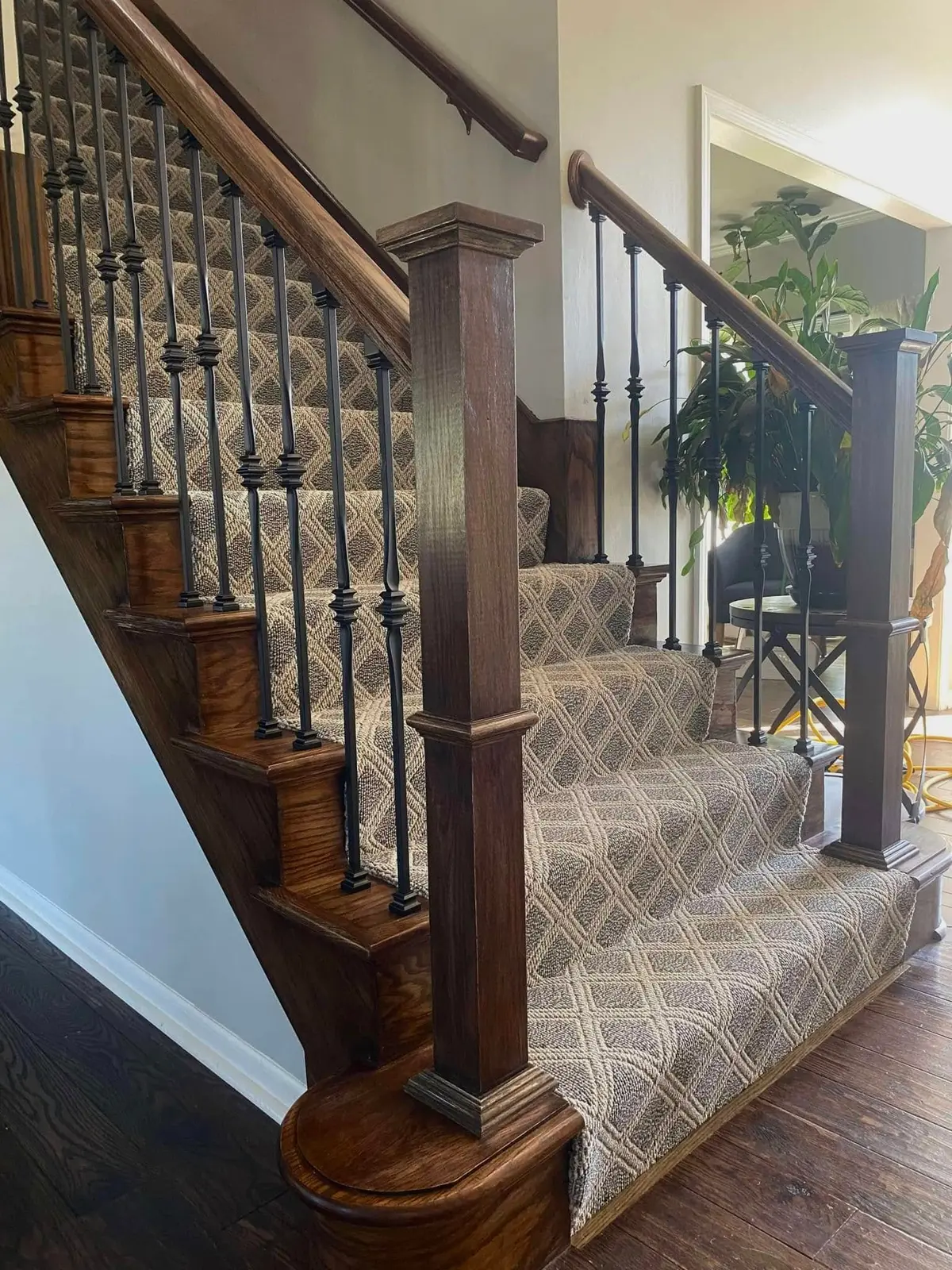 Staircase with patterned carpet runner and iron balusters by JD Build