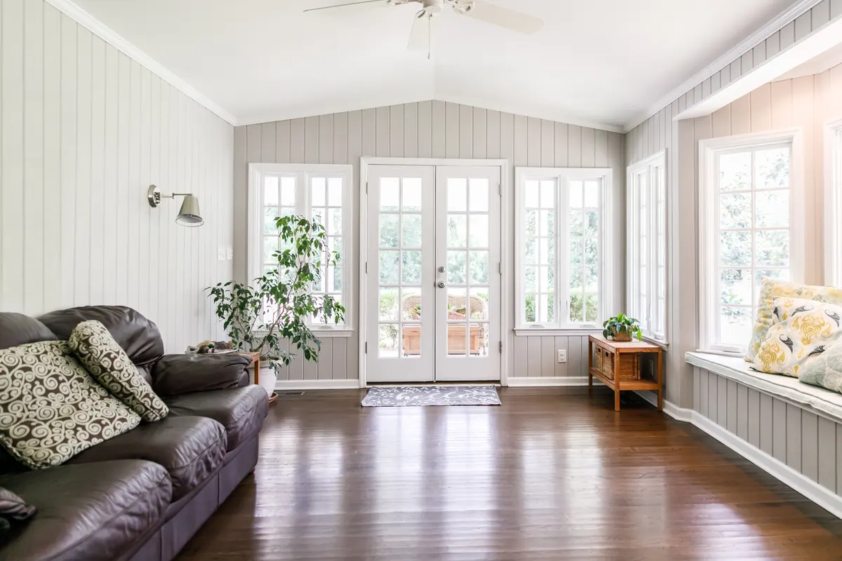 Bright sunroom home addition with a vaulted ceiling and French doors