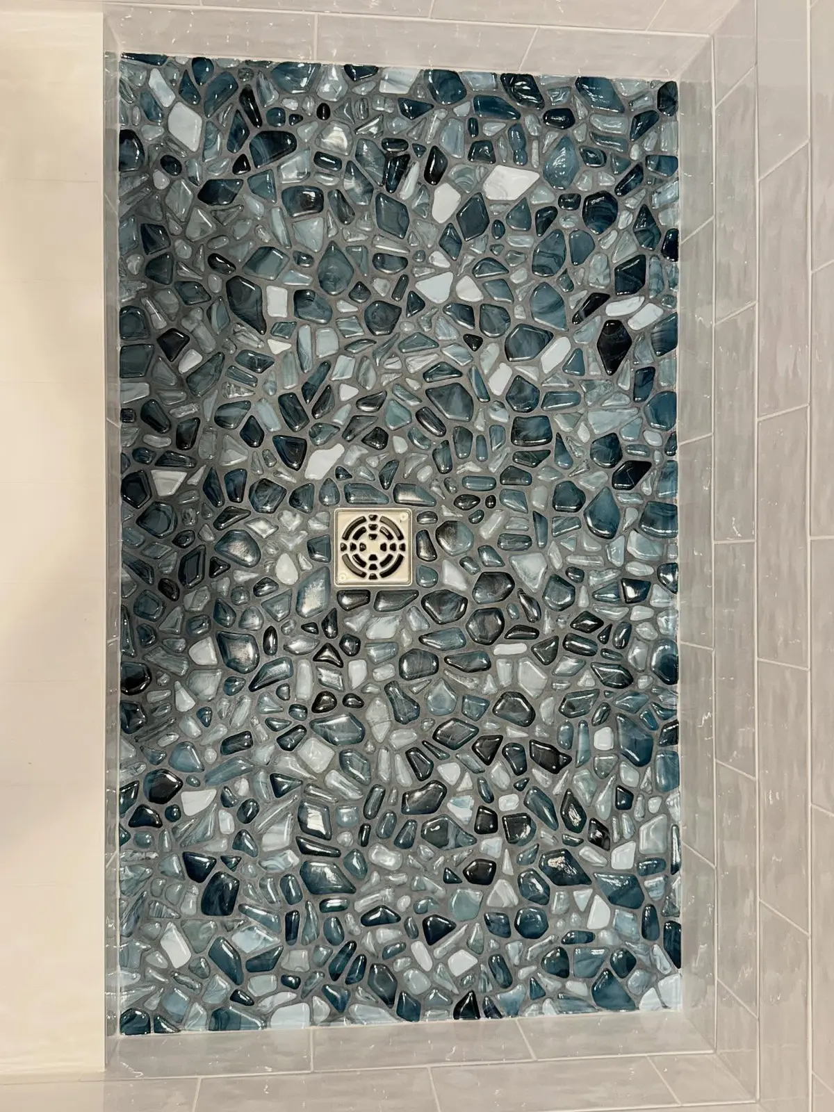 Hand-laid pebble stone and mosaic tile shower floor detail from this walk-in shower remodel