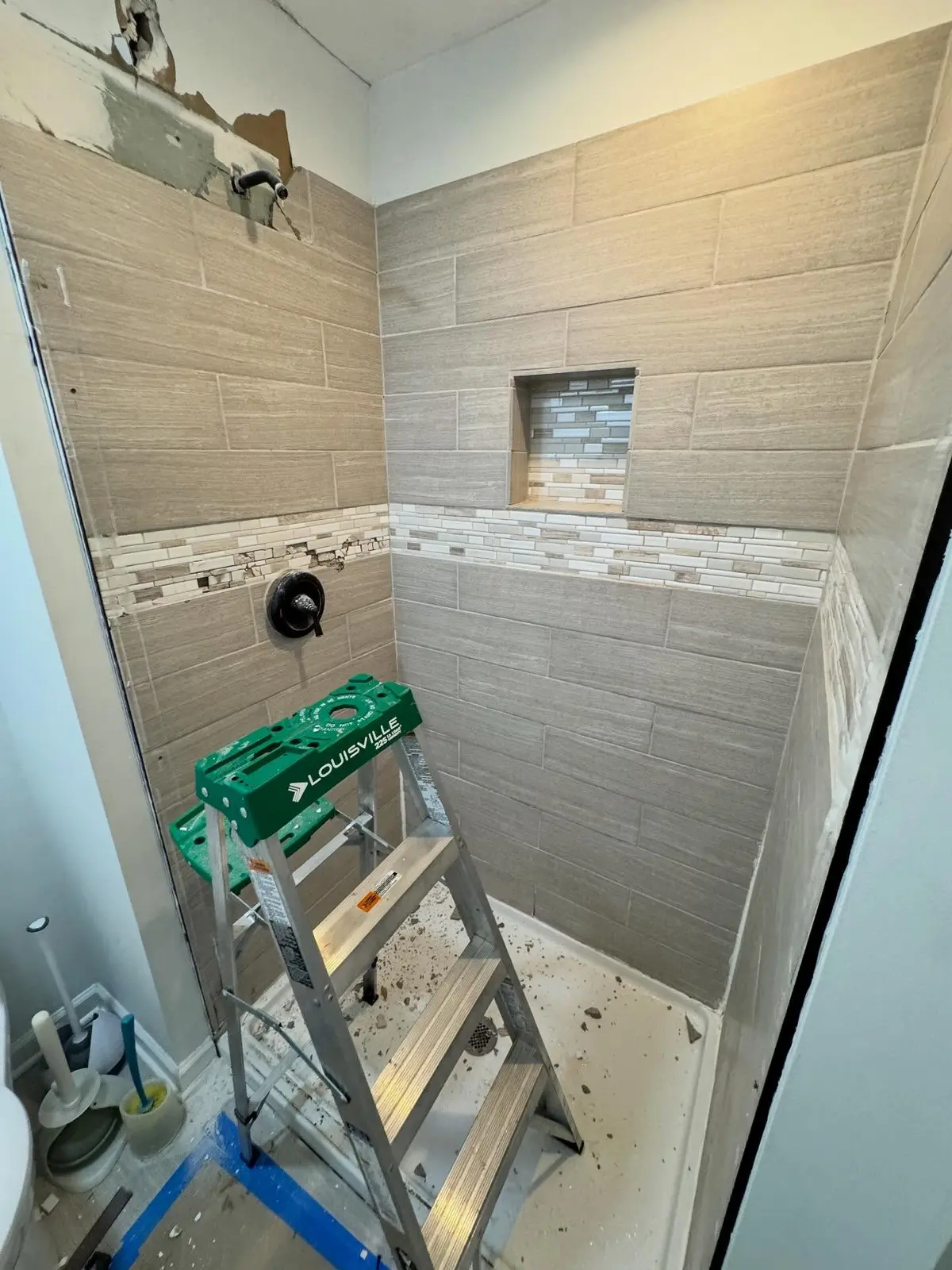 Tile shower installation in progress with decorative niche